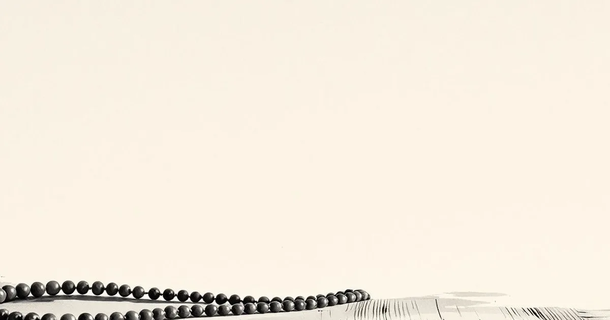 Sumi-e ink-wash illustration: a loop of simple prayer beads resting on weathered wood.